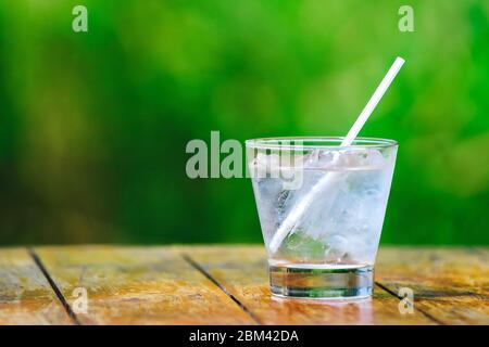 Glasglas. Mineralwasser mit Eis. Cocktailstroh. Ein grüner Hintergrund Stockfoto