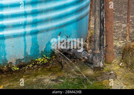Wasserleck durch Risse im Wassertank auf dem Dach des Hauses. Stockfoto