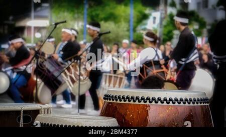 Taiko Trommeln sitzen auf der Bühne, Musiker treten im Hintergrund beim Black Ship Festival in Shimoda, Japan auf. Stockfoto