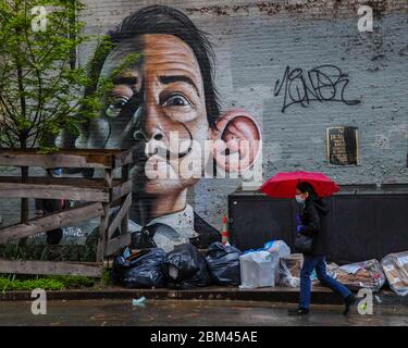 New York, New York, USA. Mai 2020. Eine Frau mit einer Schutzmaske geht vor einem Salvador Dali Wandgemälde an einer Manhattan Wand vorbei. New York City ist das Epizentrum der Coronavirus-Pandemie in den Vereinigten Staaten. Kredit: William Volcov/ZUMA Wire/Alamy Live News Stockfoto