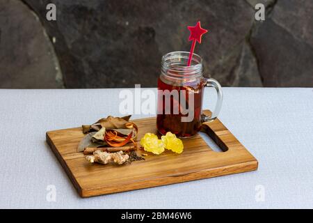 Nahaufnahme eines Einmachglas mit Kräutergetränken und verschiedenen Kräutern auf Steinhintergrund. Stockfoto
