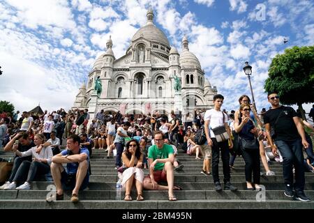 Besucher ruhen auf den Treppen auf dem Hügel mit Basilika des Heiligen Herzens von Montmartre im Hintergrund.Montmartre.Paris.Frankreich Stockfoto