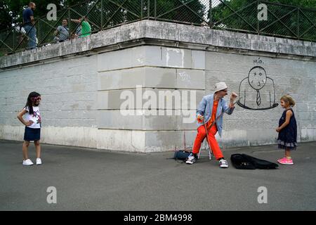 Ein Straßenkünstler Clown spielt Musik für Kinder in Montmartre.Paris.Frankreich Stockfoto