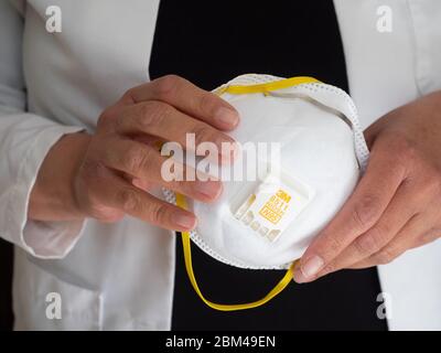 Nahaufnahme der Hände einer hispanischen oder lateinamerikanischen Frau mit einer 3M N-95 Gesichtsmaske. Stockfoto