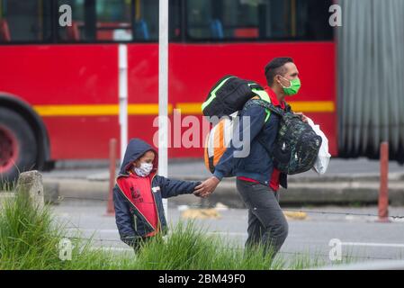 Ein Vater mit seinem Sohn geht mit Koffern durch die Straßen von Bogota und wartet darauf, wegen der Verbreitung der Korona in sein Land Venezuela zurückzukehren Stockfoto