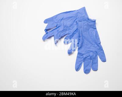 Ein Paar blaue unsterile Einweghandschuhe auf weißem Hintergrund. Das Bild hat einen Kopierbereich und eine geringe Schärfentiefe. Stockfoto