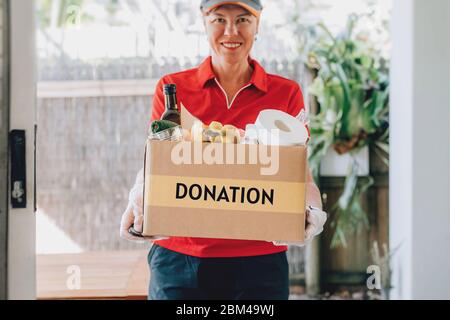Lieferung Frau in Schutzhandschuhen liefert Papiertüte mit Lebensmitteln. Gesundheitsschutz, Sicherheit und Pandemie. Stockfoto