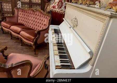 Vintage Retro-Zimmer-Einstellung mit Sofa, Accessoires, alte rostig weißen Klavier. Ideal für Postkarte. Altes Wohnzimmer, französischer Stil, viktorianische Details Stockfoto