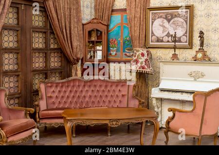 Vintage Retro-Zimmer-Einstellung mit Sofa, Accessoires, alte rostig weißen Klavier. Ideal für Postkarte. Altes Wohnzimmer, französischer Stil, viktorianische Details Stockfoto