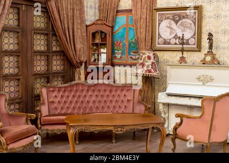 Vintage Retro-Zimmer-Einstellung mit Sofa, Accessoires, alte rostig weißen Klavier. Ideal für Postkarte. Altes Wohnzimmer, französischer Stil, viktorianische Details Stockfoto