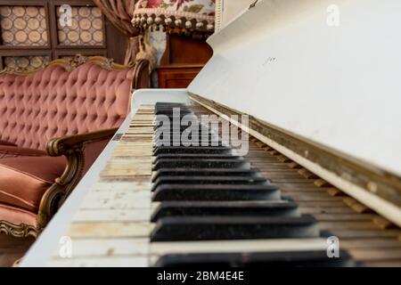 Vintage Retro-Zimmer-Einstellung mit Sofa, Accessoires, alte rostig weißen Klavier. Ideal für Postkarte. Altes Wohnzimmer, französischer Stil, viktorianische Details Stockfoto