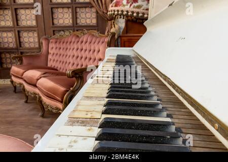 Vintage Retro-Zimmer-Einstellung mit Sofa, Accessoires, alte rostig weißen Klavier. Ideal für Postkarte. Altes Wohnzimmer, französischer Stil, viktorianische Details Stockfoto