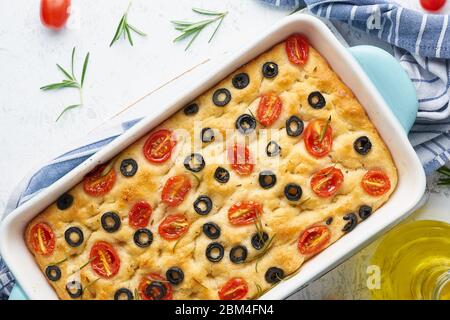 Focaccia mit Tomaten, Oliven und Rosmarin in Kasserolle, Draufsicht. Traditionelles italienisches Fladenbrot Stockfoto