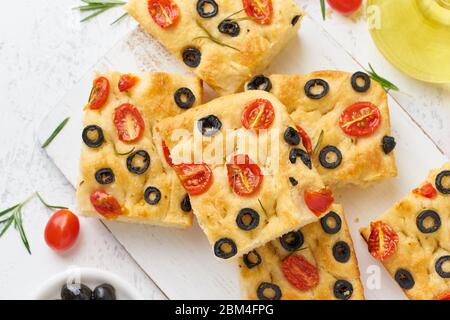 In Scheiben geschnittene Focaccia mit Tomaten, Oliven und Rosmarin. Traditionelles italienisches Fladenbrot. Stockfoto