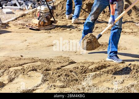 Ein Arbeiter schaufelt Sand im Arbeitsbereich. Stockfoto