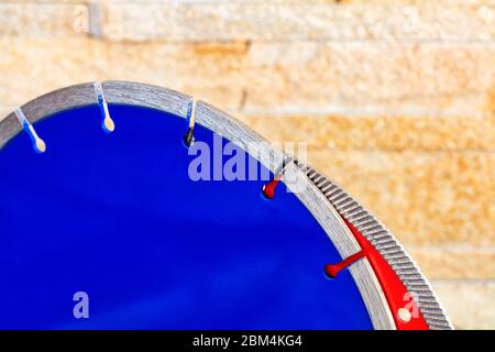 Segmente von Diamant-Schneidescheiben auf Granit und Stahlbeton vor dem Hintergrund einer gelben Sandsteinwand in Unschärfe. Stockfoto