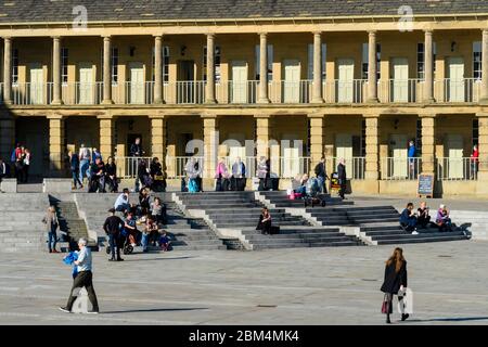 Historischer Piece Hall Hof (sonnige piazza, Besucher entspannen, auf Treppen sitzen & spazieren gehen, Säulenbögen) - Halifax, West Yorkshire, England, Großbritannien. Stockfoto