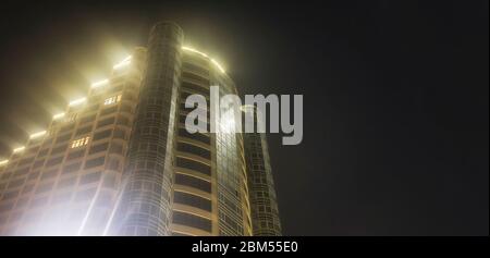 Odessa, Ukraine - April 03 2020: Bodenaufnahmen modernes Stadthaus mit Neonlicht gegen den Nachthimmel Raum für Text Stockfoto
