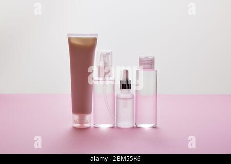 Set von kosmetischen Flaschen und kosmetische Creme Tube auf rosa und grau Hintergrund Stockfoto