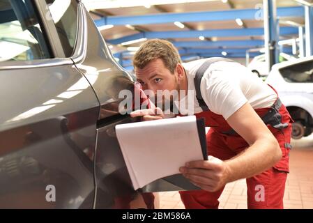 Automechaniker untersucht Unfallfahrzeug in einer Werkstatt nach dem Lackieren Stockfoto