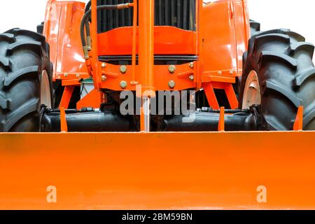 Nahaufnahme vor einem großen orangefarbenen Traktor, Traktor für die Arbeit auf großen landwirtschaftlichen, isoliert auf weißem Hintergrund. Stockfoto