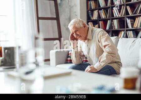 Älterer Mann allein sitzt am Bibliothekstisch Nahaufnahme mit Migräne verärgert Stockfoto