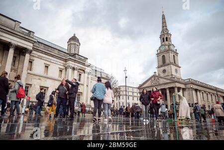 Touristen in einem nassen Trafalgar Square, der von der St. Martin-in-the-Fields Church und der National Gallery, London, dominiert wird. Stockfoto