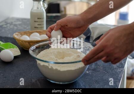 Der junge Mann bricht in der Küche Eier für Teig. Stockfoto