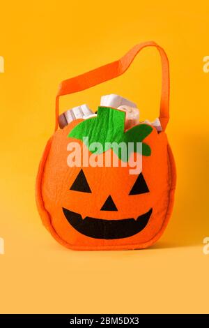 Halloween Kürbis Tasche mit Süßigkeiten innen isoliert auf gelbem Hintergrund Stockfoto