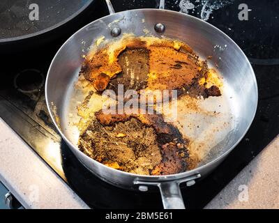 Steelpfanne mit Kruste von Lebensmitteln verbrannt beim Kochen auf Elektroherd in der Küche Stockfoto