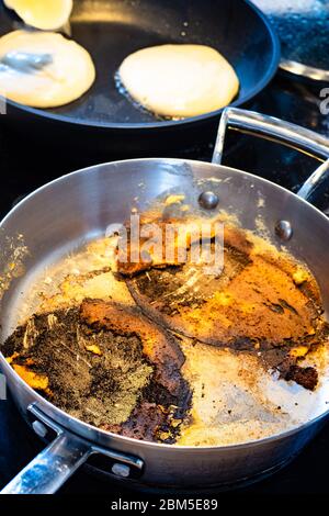 Steelpfanne mit Überresten von verbrannt beim Kochen Pfannkuchen auf Elektroherd in der Küche Stockfoto