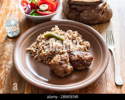 russisches Mittagessen mit gebratenem Kotleta (panierte Hacksteaks), Beilage aus gekochtem Buchweizenbrei und Gemüsesalat auf schäbiges Holztisch Stockfoto