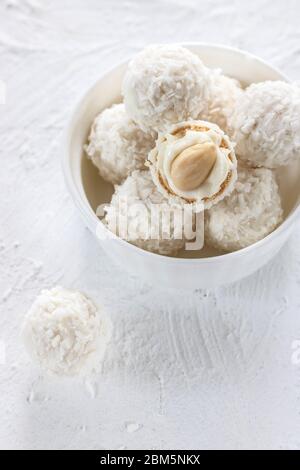 Bonbons mit Nougat und Mandeln in Kokosflocken auf hellem Hintergrund Stockfoto
