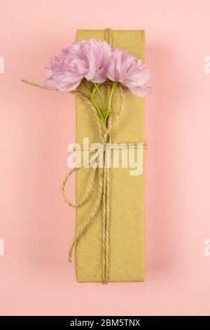 Geschenkboxen aus Bastelpapier und Bläserband mit rosa Blüten auf dem rosa Hintergrund, Draufsicht, Nahaufnahme Stockfoto