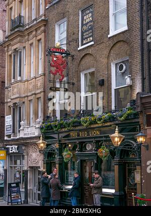 Männer rauchen außerhalb des Red Lion Pubs in der York Street. The Red Lion Public House in Duke of York Street London GB Großbritannien Stockfoto