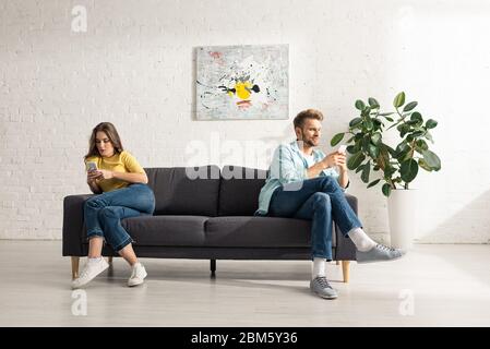 Junges Paar mit Smartphones auf der Couch zu Hause Stockfoto