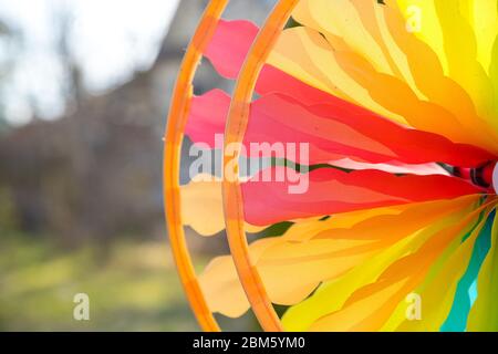 Bunte Windrad Spinnen im Wind vor einem natürlichen grünen Hintergrund.Fokus auf der Mitte der Windrad.Bunte Spielzeug. Fun Party Dekorationen Stockfoto