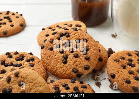 Zusammensetzung mit Chip Cookies, Milch und Karamell auf weißem Holztisch Stockfoto