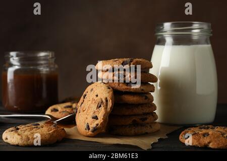 Zusammensetzung mit Chip Cookies, Milch und Karamell auf Holztisch Stockfoto