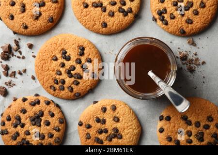 Zusammensetzung mit Chip Cookies und Karamell auf grauem Tisch Stockfoto