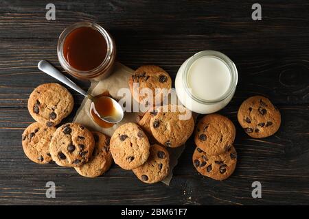 Zusammensetzung mit Chip Cookies, Milch und Karamell auf Holztisch Stockfoto