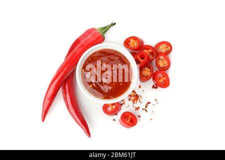 Chilischote und Schüssel mit Sauce auf weißem Hintergrund isoliert Stockfoto