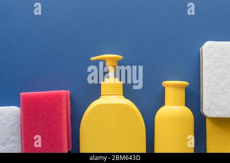 Buntes Reinigungsset für verschiedene Oberflächen auf blauem Hintergrund. Reinigungskonzept mit Zubehör.Plastikflaschen, Waschmittelbehälter, Mikrofaser Stockfoto