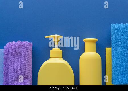Buntes Reinigungsset für verschiedene Oberflächen auf blauem Hintergrund. Reinigungskonzept mit Zubehör.Plastikflaschen, Waschmittelbehälter, Mikrofaser Stockfoto