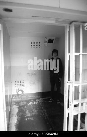 Eine einsame Figur steht in einer abgenutzten Gefängniszelle unter dem wachsamen Auge einer Überwachungskamera in Alcatraz San Francisco USA Stockfoto