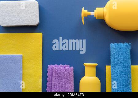 Buntes Reinigungsset für verschiedene Oberflächen auf blauem Hintergrund. Reinigungskonzept mit Zubehör.Plastikflaschen, Waschmittelbehälter, Mikrofaser Stockfoto