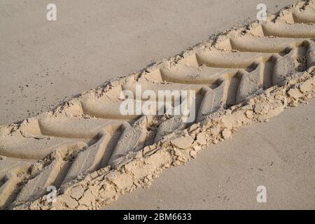 Autospuren im Sand Fußabdruck durch die Passage des Traktors am Wüstenstrand links Stockfoto