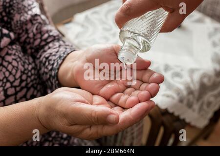 Eau de Turkish Lemon Cologne goss auf die Hand der alten Frau und desinfizierte die Hand und tötete die Viren Stockfoto