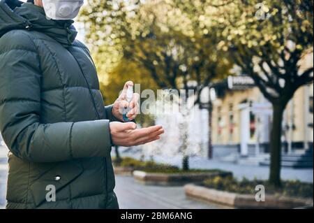 Beschnittene Nahaufnahme von Händen einer Frau, die auf der Straße ihre Hände mit Handwaschspray als vorbeugende Hygienemaßnahme gegen Infektionen abwischt. Vorbeugende Maßnahmen während der Quarantäne Stockfoto