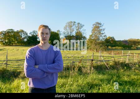 Junger schöner Mann, der in einer ruhigen Grasebene mit der Natur steht Stockfoto